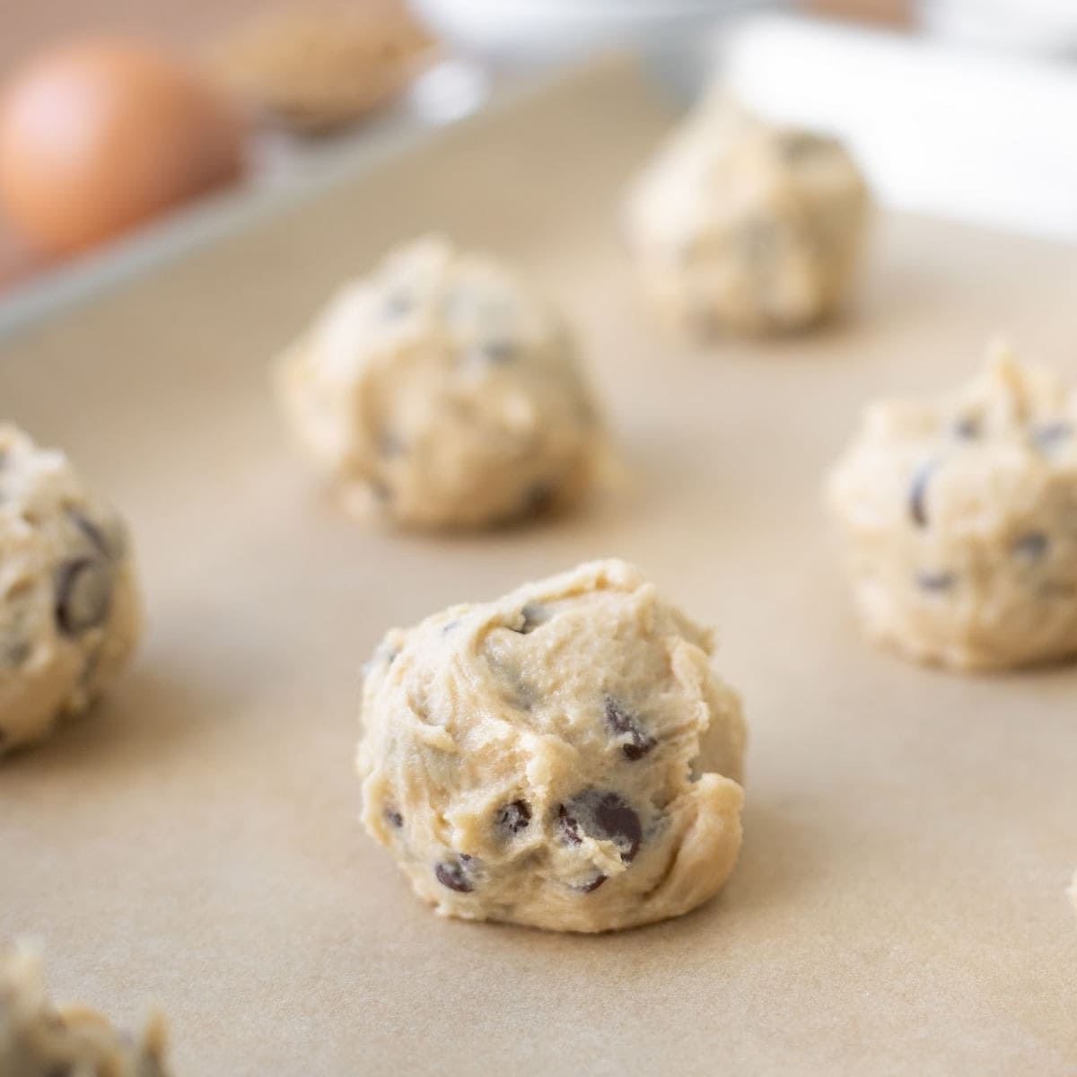 Cookie dough balls on parchment lined baking sheet.