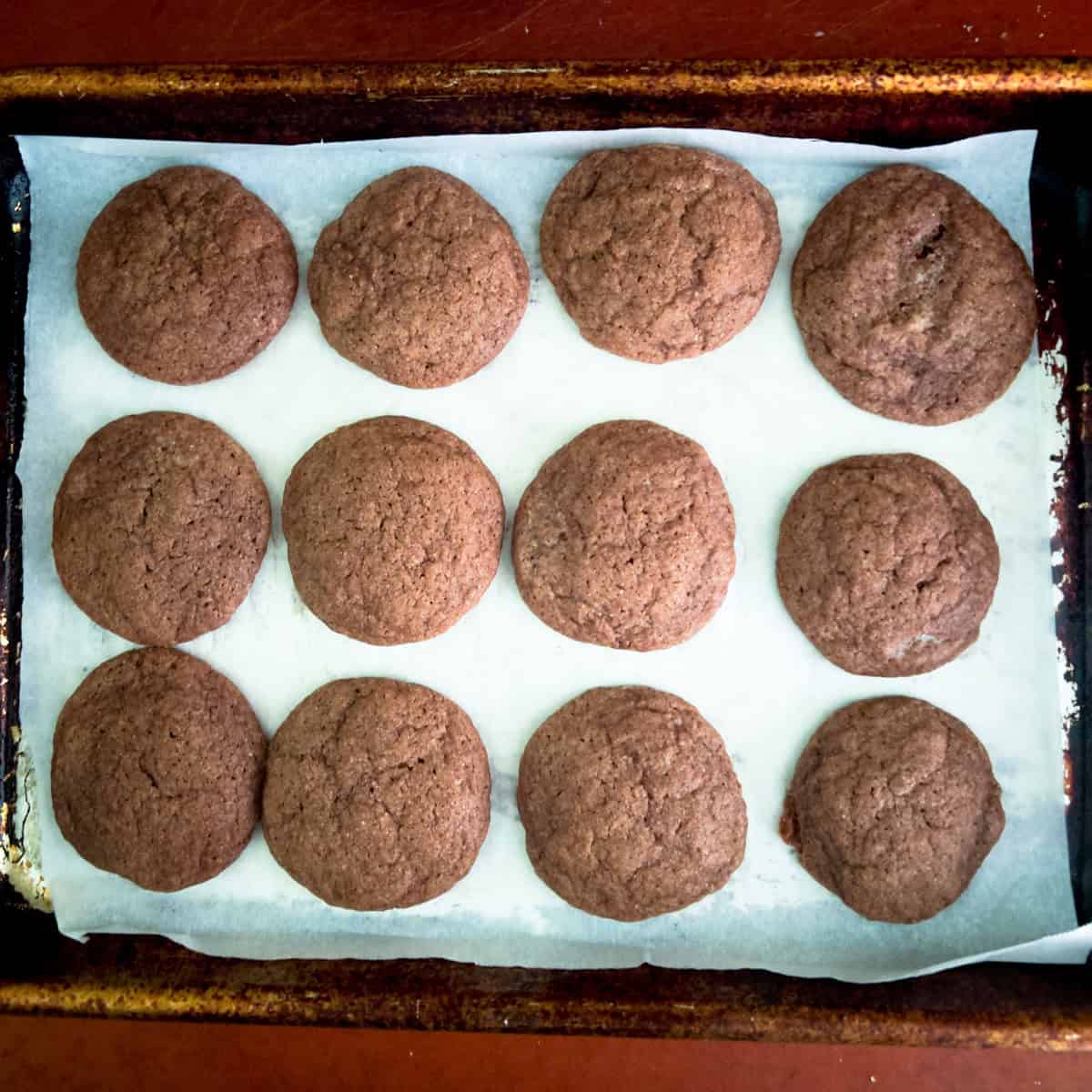 Baked chocolate snickerdoodle cookies on parchment lined baking sheet.