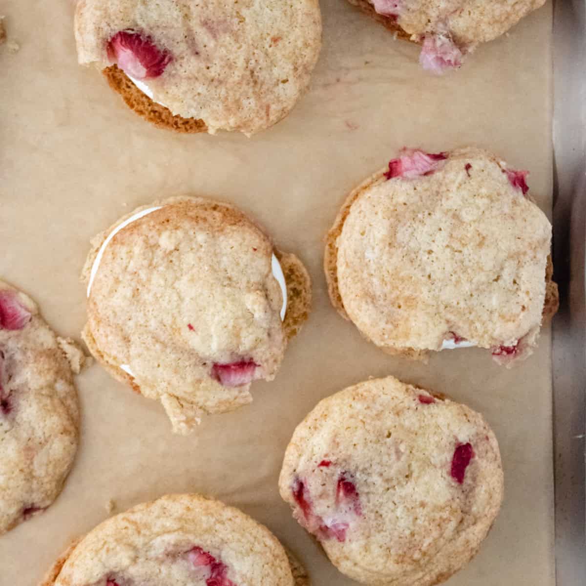 Strawberry sandwich cookies on parchment lined baking sheet.