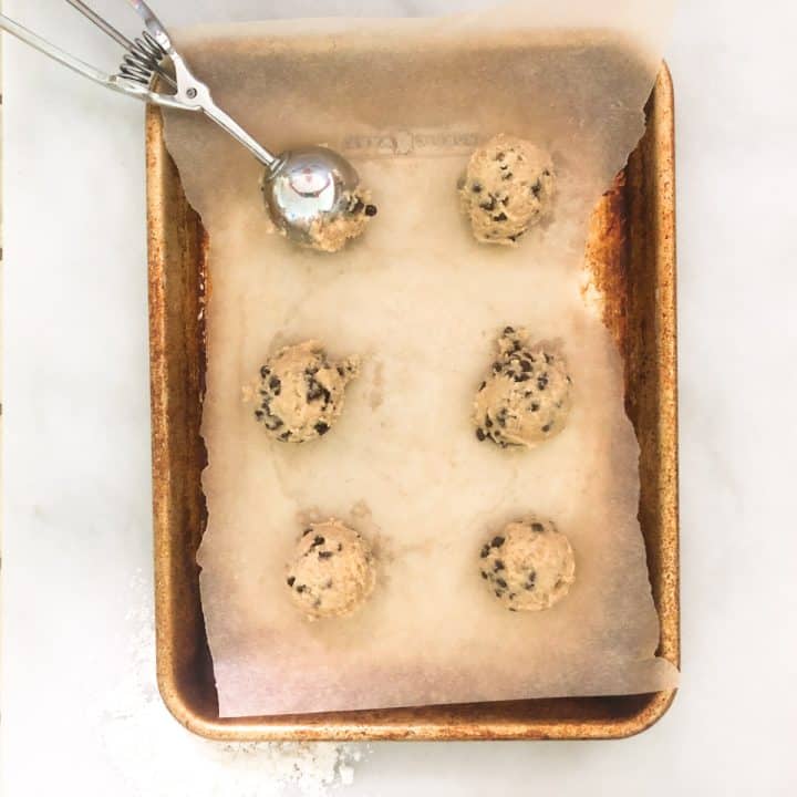 Cookie dough balls on parchment paper lined baking sheet.