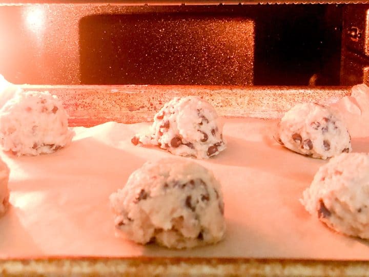 Chocolate chip cookie dough balls baking in oven.