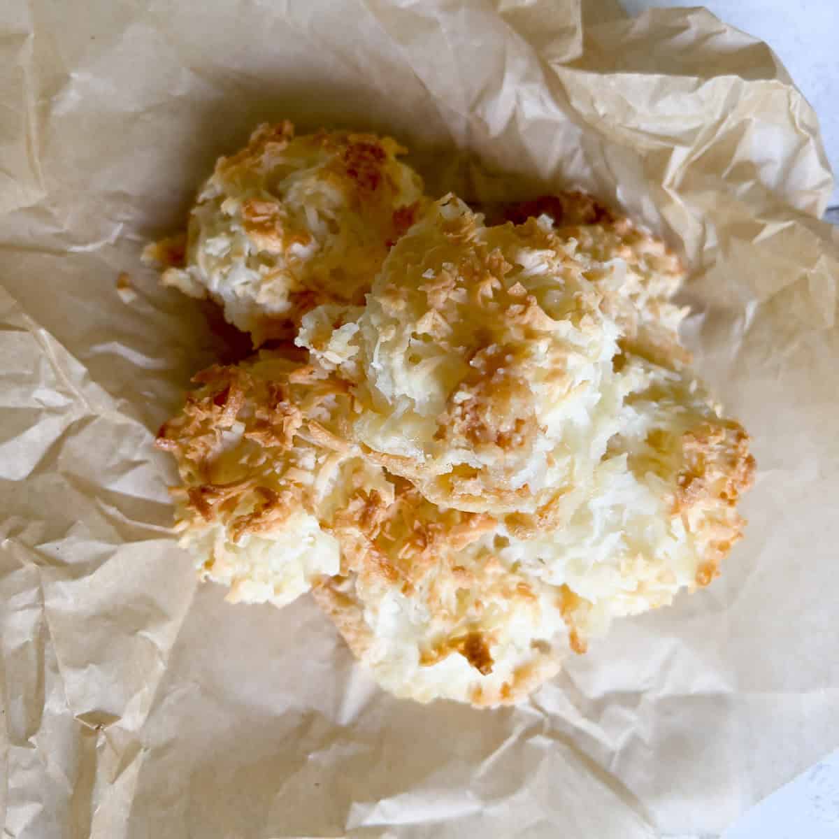 Pile of homemade coconut macaroons on parchment paper.