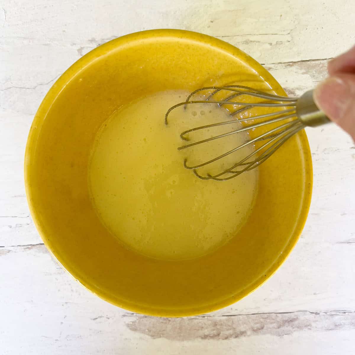 Eggs and sugar mixture in yellow bowl.