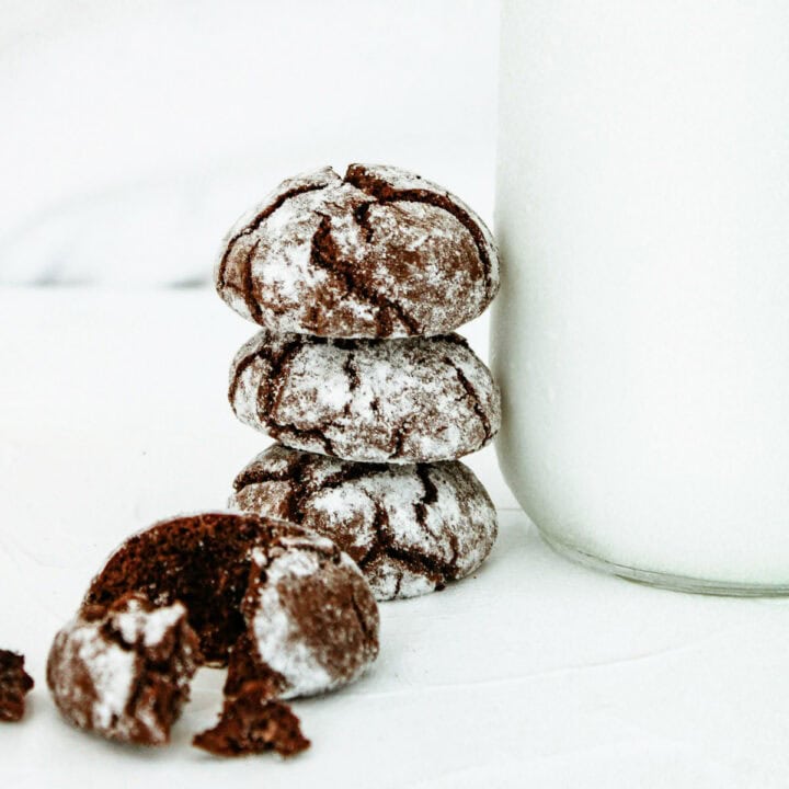 Stack of chocolate crinkle cookies against a jar of milk.