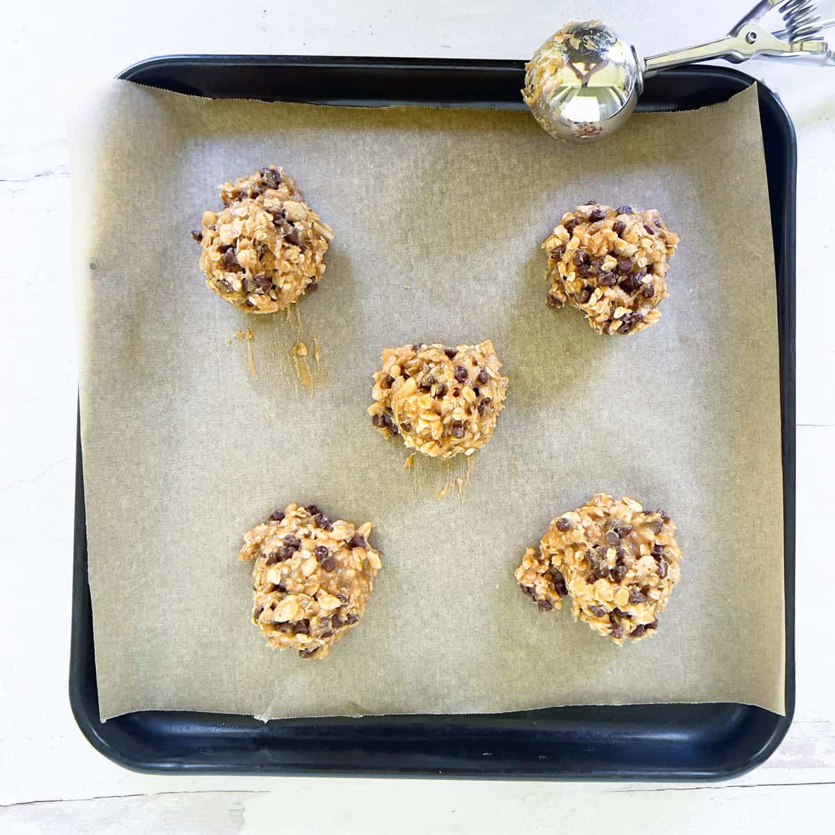 Cowboy cookie dough on square parchment lined baking sheet.