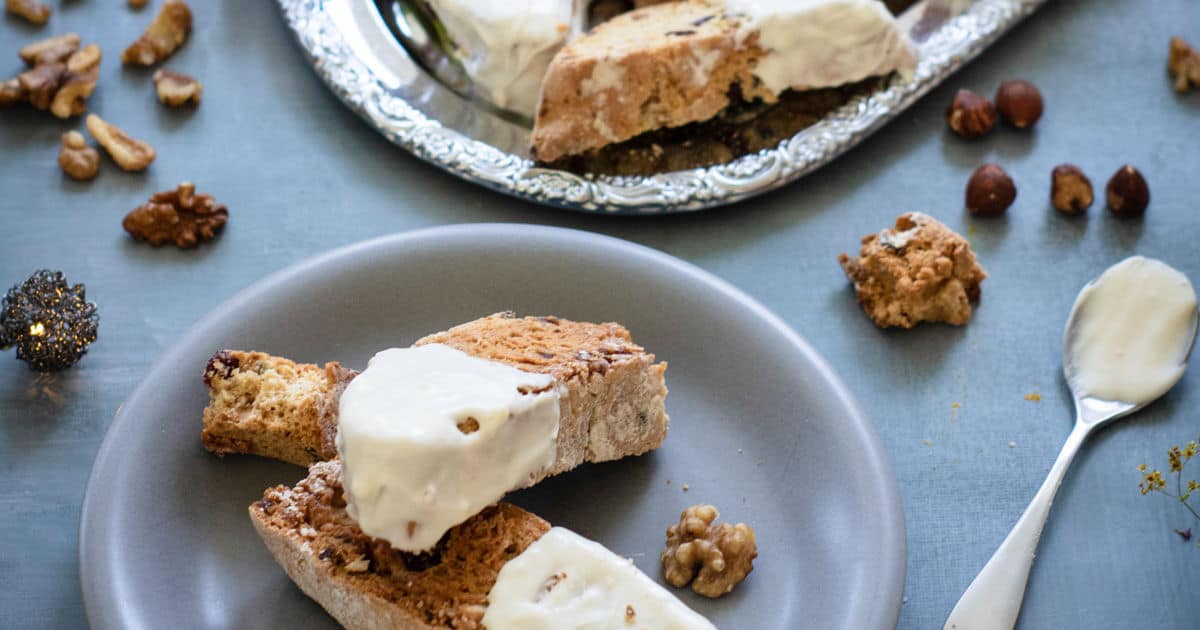 Cranberry biscotti dipped in white chocolate on small plate.