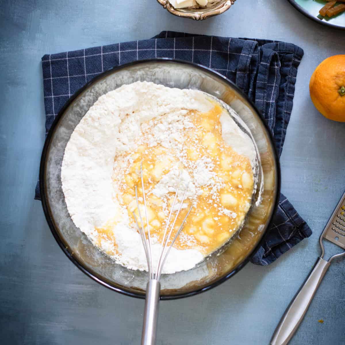 Eggs and flour in bowl with whisk.