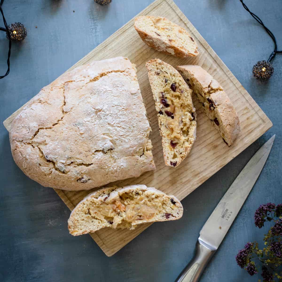 Baked partially sliced loaf of Biscotti on wood board.