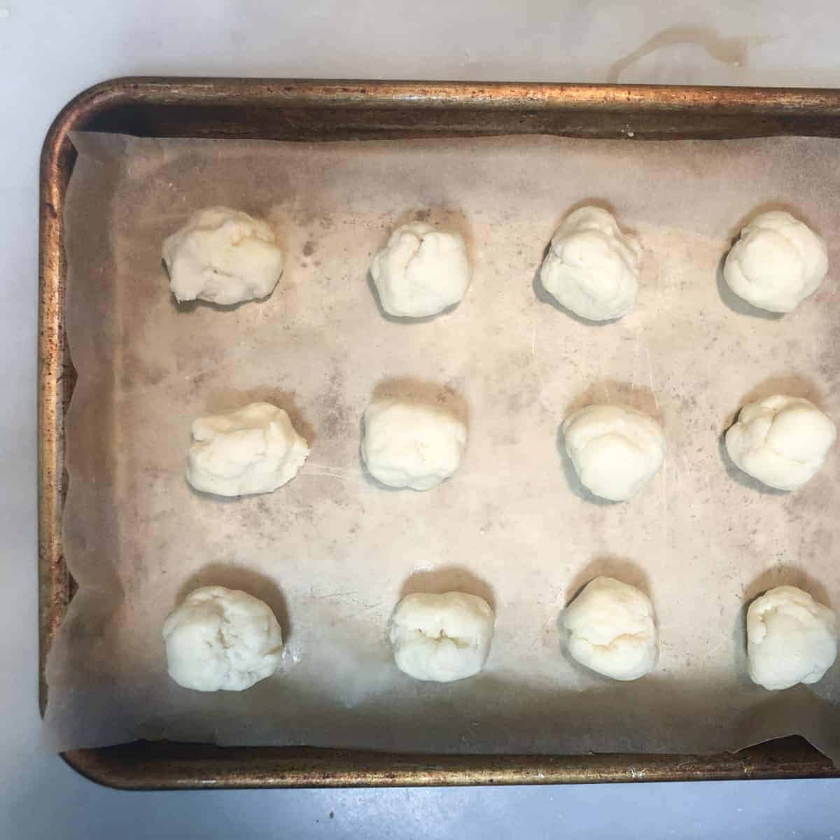 Cream cheese lemon curd cookie dough balls on baking sheet.