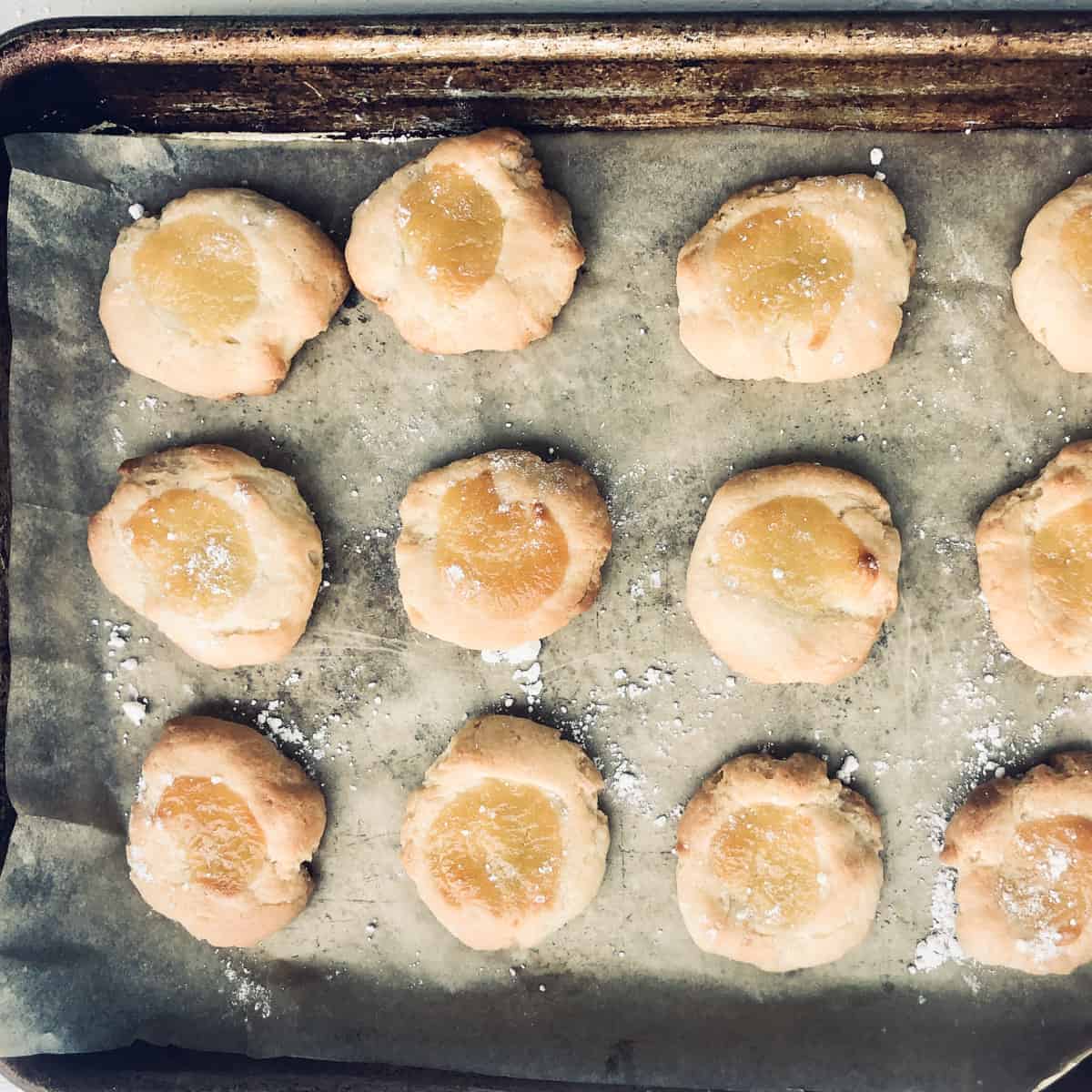 Baked lemon curd thumbprint cookies on baking sheet.