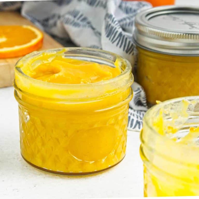 Small mason jars of orange curd on table.