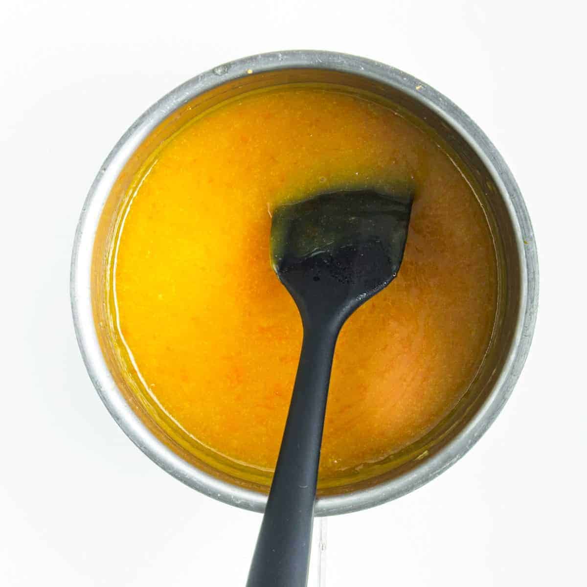 Thickening orange curd in saucepan.