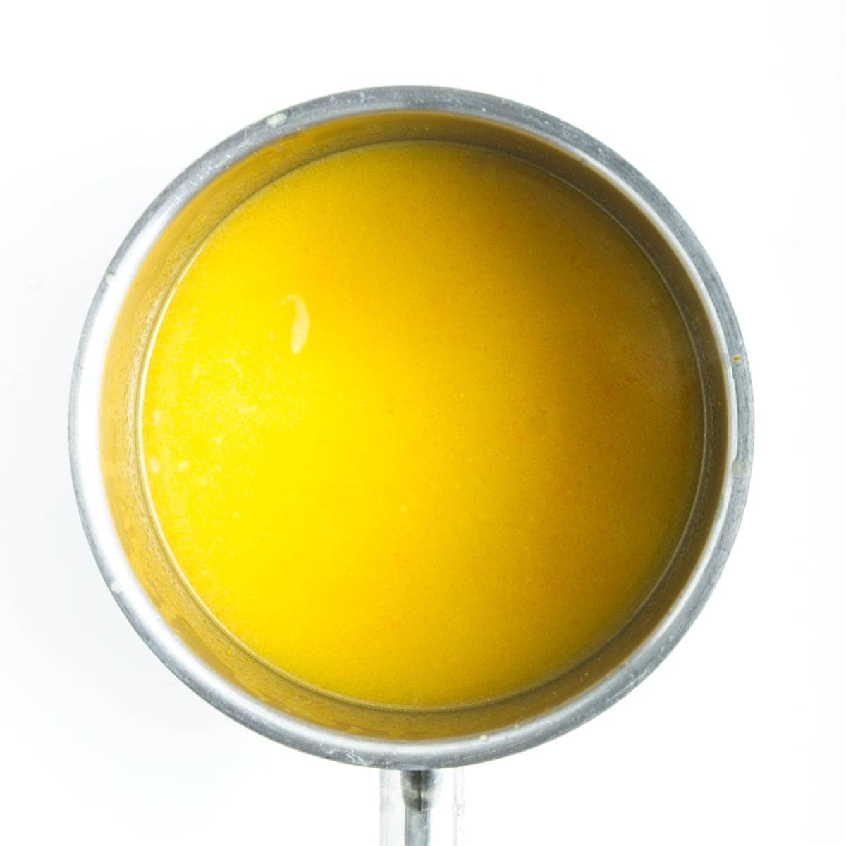 Orange Curd cooking in small saucepan.