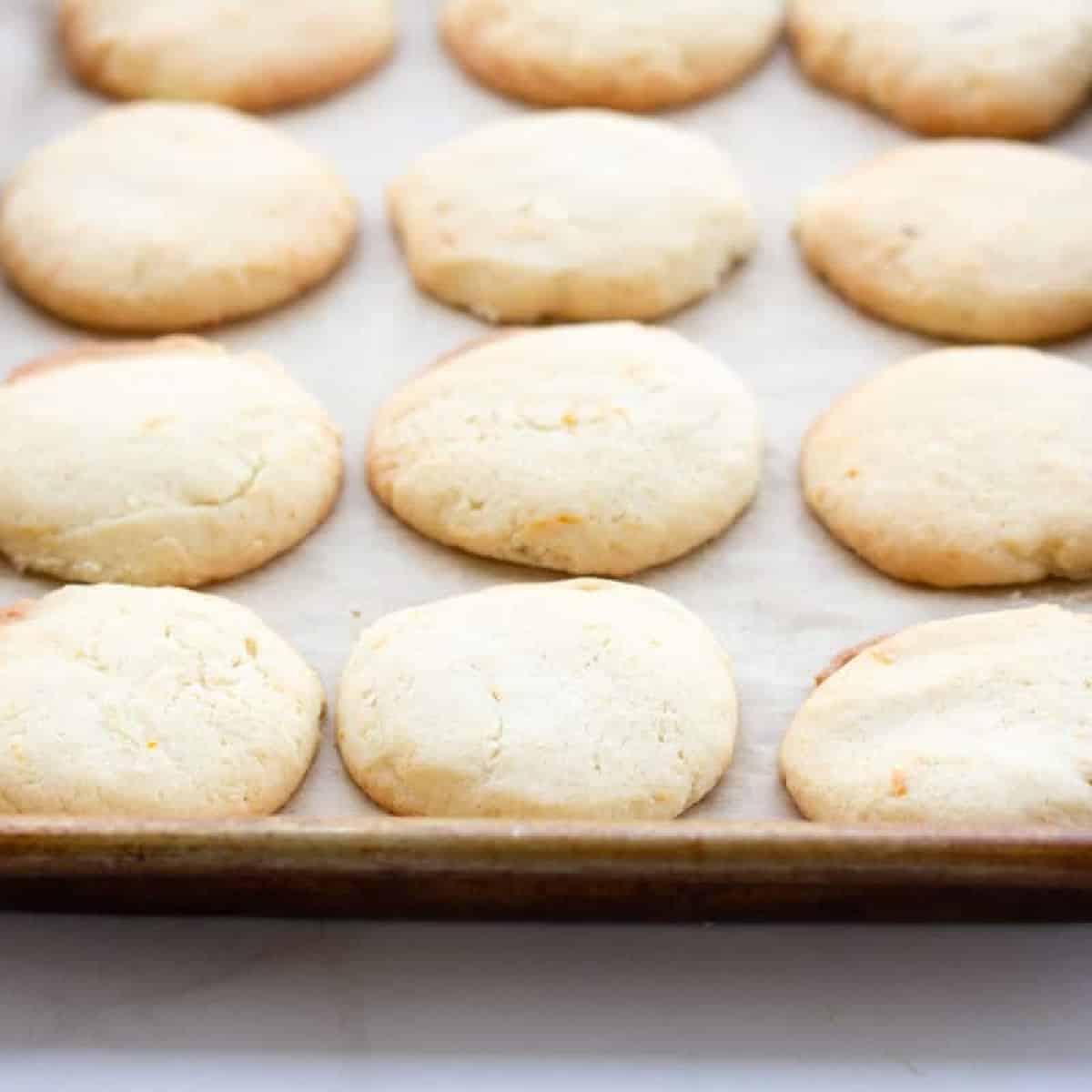 Baked orange flavored sugar cookies on baking sheet.